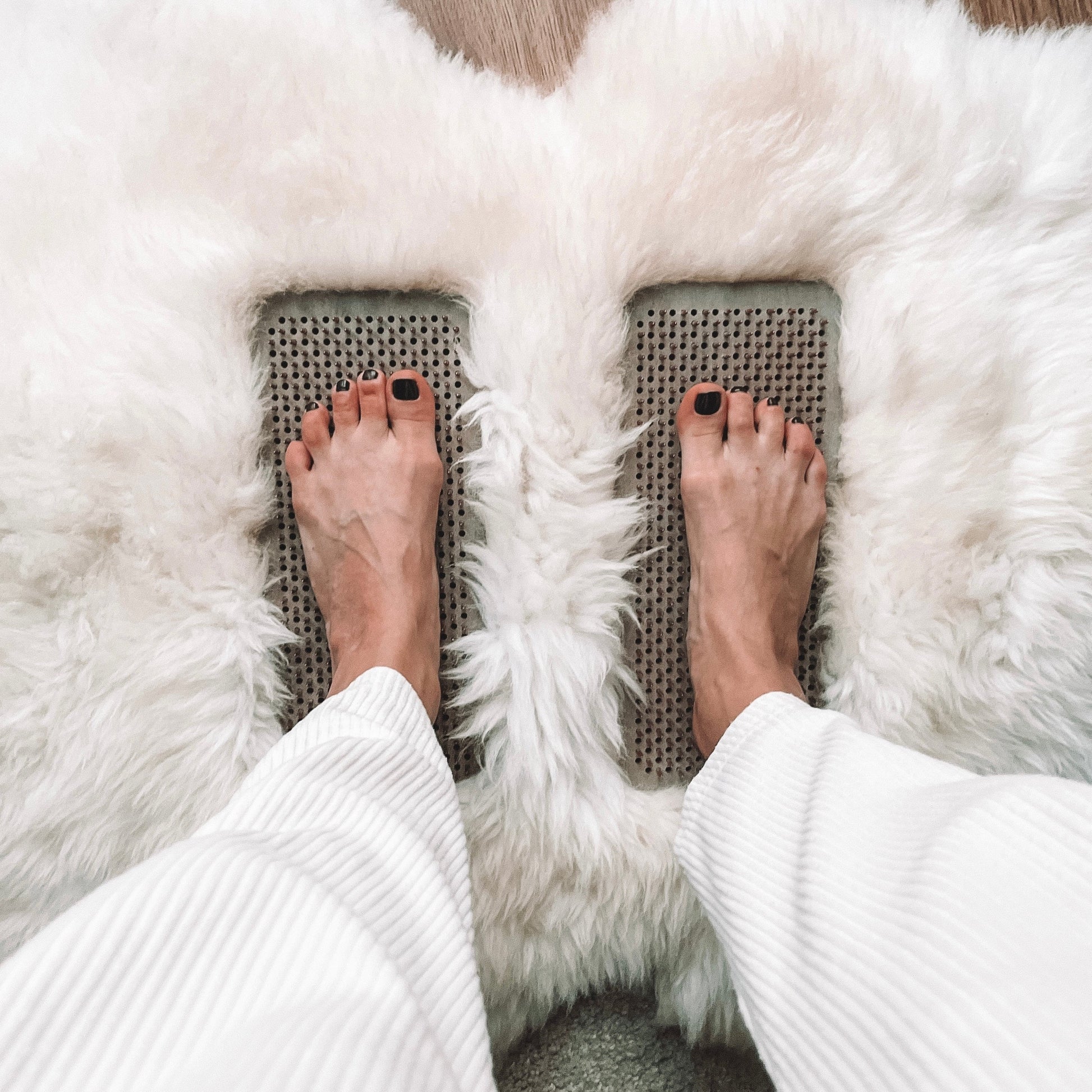 Person standing on the Yin-Yang Sadhu Board to stimulate reflexology points and enhance circulation.